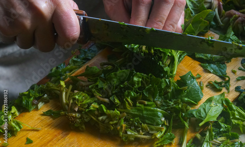 Top view of hands chopping fresh green spinach for traditional Uzbek somsa.