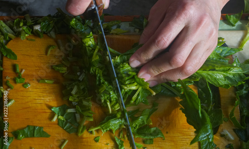 Top view of hands chopping fresh green spinach for traditional Uzbek somsa.