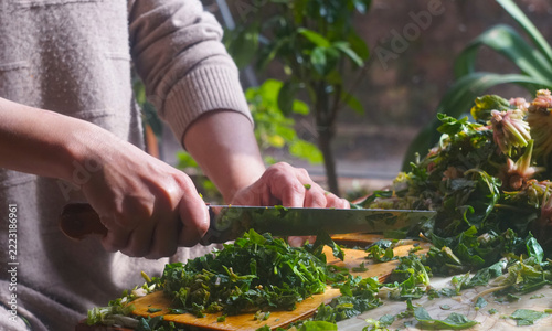 Woman cutting fresh spinach for traditional Uzbek green somsa.