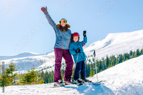 Sporty woman teach skiing child boy at mountains alpine winter resort.Young mother,coach,trainer learn little son kid riding downhill,family,enjoy extreme sport activities recreation