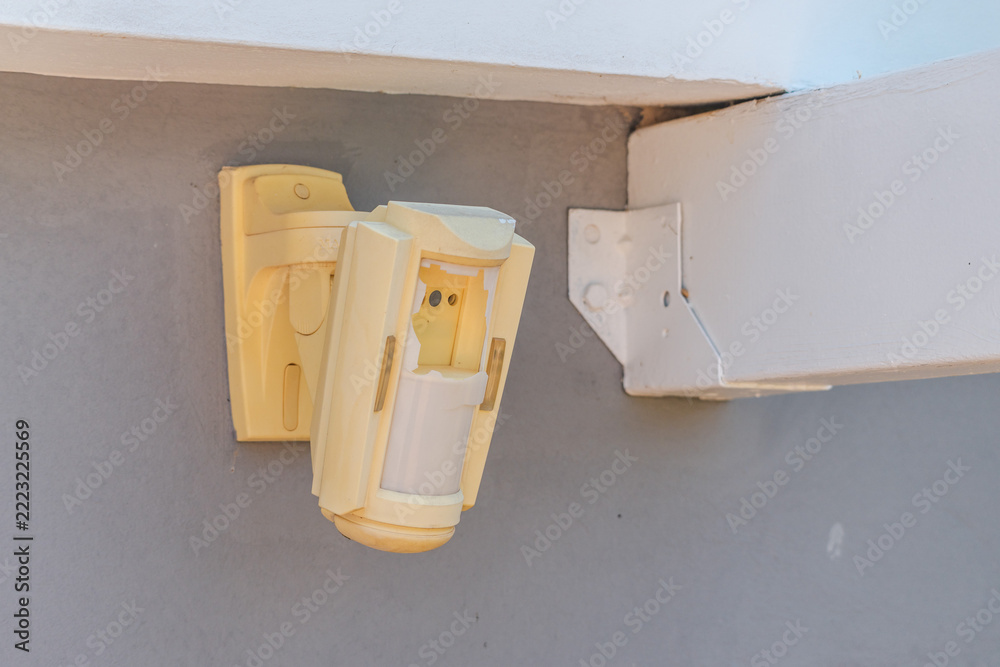 Fotografie Vandalized Motion Sensor Hanging from Exterior Wall