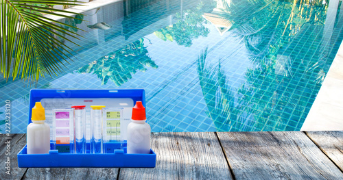 Water tester test kit over crystal clear swimming pool water background, outdoor day light