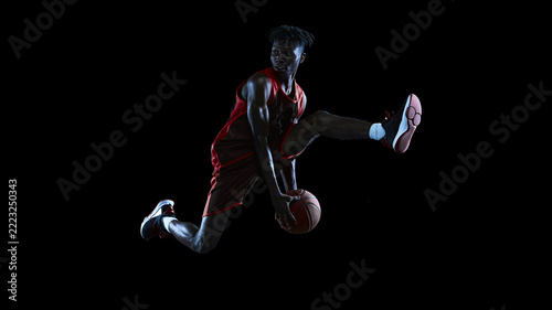 Young male basketball athlete jumping with ball beneath extended leg on black studio background with focused gaze. Freestyle competitions, sneaker retail concept.