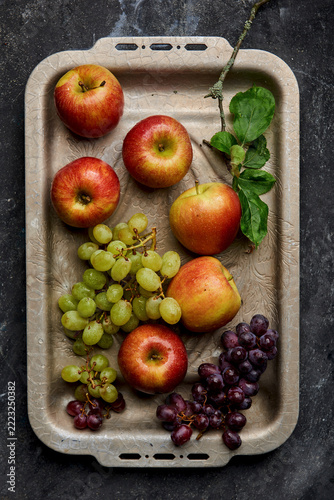 Braeburn apples and green and red grapes on a decorative tray