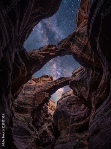 Celestial spectacle illuminating natural rock arches within a mysterious canyon, showcasing the breathtaking beauty of the starlit desert night and ancient geological formations