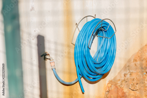 Blue Water Hose Rolled on Wall Mounted Rack
