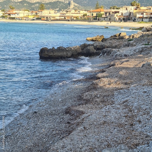  Picturesque shoreline with pebbles, limestone rocks and calm waters near a seaside village. Attractive coastal destination highlighting Mediterranean charm and natural beauty.
