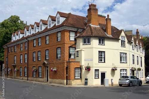 Historic multi-story residential buildings featuring traditional red brick, cream-rendered facades, dormer windows, and chimneys along a street corner in Eton, near Windsor, Berkshire, England.