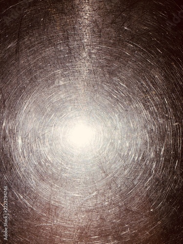 A close-up view of a heavily scratched metallic surface shows concentric circular patterns.