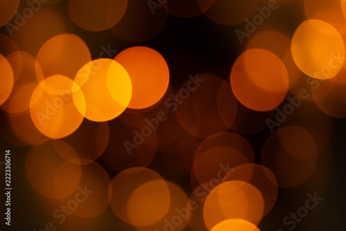 Abstract orange and golden bokeh lights glowing against a dark background creating a warm atmosphere.
