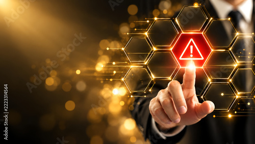 Businessman touching a futuristic holographic warning icon on a digital interface, symbolizing cybersecurity and data protection concerns in technology.