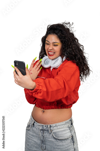 Young woman laughing holding smartphone on pink background