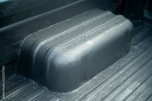 Close up of wet truck bed liner surface with raindrops after a storm.
A high-quality close-up photograph capturing the textured black or dark grey truck bed liner interior of a pickup truck