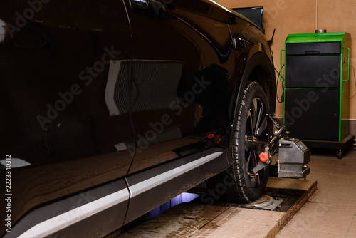 Car on a vehicle alignment machine at a service center during a routine maintenance check. Wheel alignment and alignment on the car service platform.