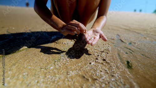 Woman examining wet sand in her palm at the shoreline