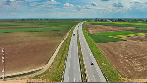 Aerial view of highway crossing green agricultural fields