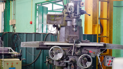 Industrial metal milling machine with a control panel and mechanical components inside a manufacturing factory.