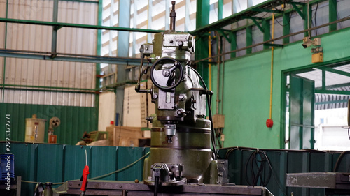 Industrial metal milling machine with a control panel and mechanical components inside a manufacturing factory.