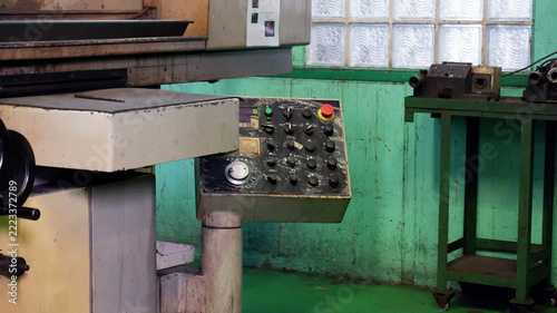 Industrial metal milling machine with a control panel and mechanical components inside a manufacturing factory.