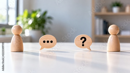 Wooden peg figures facing each other with speech bubble and question mark symbols for communication concept image.