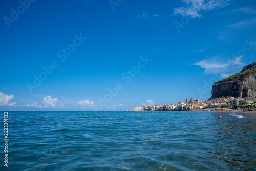 Famous beach of Cefalu, located on the northern coast of Sicily, Italy, with the historic village and its seafront buildings in the background