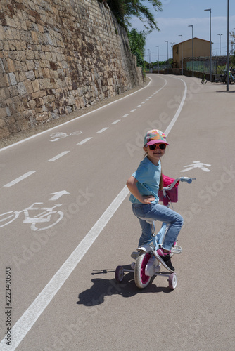 Child learning to ride bike with training wheels