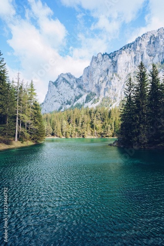 Beautiful landscape with a lake in a forest and amazing high rocky mountains in the background