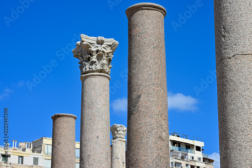 Low Angle Ancient Colonnade Detail with One Corinthian Order Capital and Modern Buildings in Lower Background