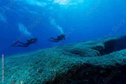 Two divers explore the rocky seabed