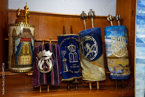 Row of ornately decorated Torah scrolls displayed in a synagogue ark.