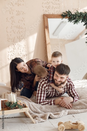 Young family in plaid shirts laying on a blanket and hugging