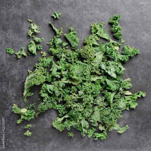 Chopped kale flat lay scattered on dark grey tile background