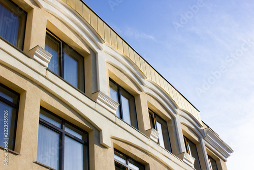 A stone building with windows. Architectural design of a modern classical building, an office, a commercial building on the skyline, with a cultural urban style.