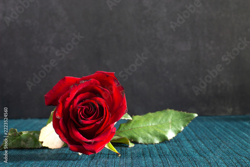red roses with green leaves on wooden background. valentine 's day card