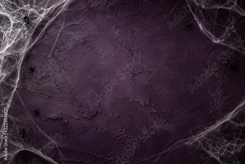 Spooky Halloween cobwebs and black spiders framing a textured dark purple wall