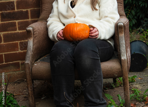 Woman sitting in old chair holding a pumpkin