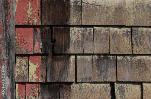 Interesting background of old weathered wood shingle siding with peeling red paint