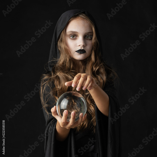 A young witch holding a clear crystal ball in hands