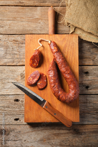 Spanish Chorizo Rests on a Wooden Board With Knife and Slices Nearby
