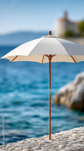 Beachside white umbrella on rocky shore with ocean in background