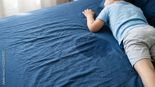Child Sleeping on Blue Bed Sheet with Wet Stain Showing Bedwetting Problem and Nocturnal Enuresis in Children