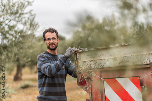 agricultural workers pose beside the trailer among olive trees