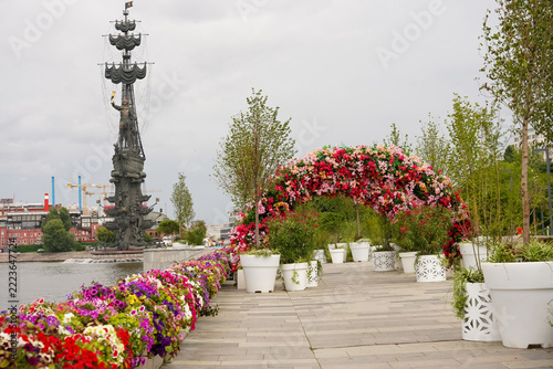 Floral arch and colorful flower decoration on river embankment with Peter the Great monument in background. Moscow city sightseeing and summer garden festival concept for tourism and travel