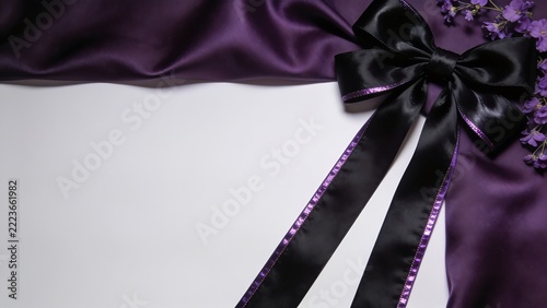 Black mourning ribbon with purple edge on dark violet silk drape.