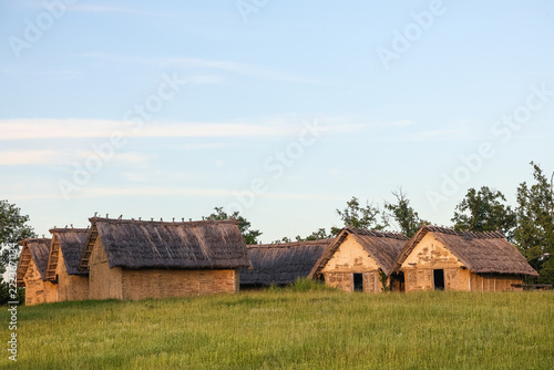 Traditional Thatched Cottages on a Green Meadow in a Rural Historic Village at Sunset, Sopot culture,  Vinkovci, Croatia