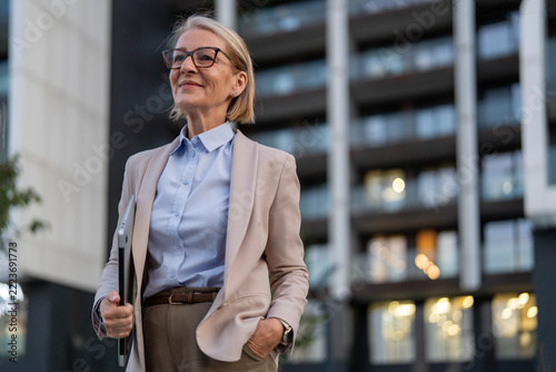Mature businesswoman looking forward holding laptop