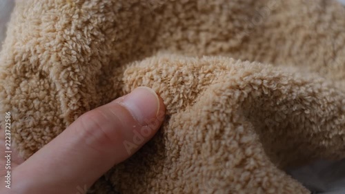 Close up macro shot of a hand touching soft beige microfiber fabric texture