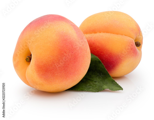 Two fresh ripe apricots with green leaf isolated on white background