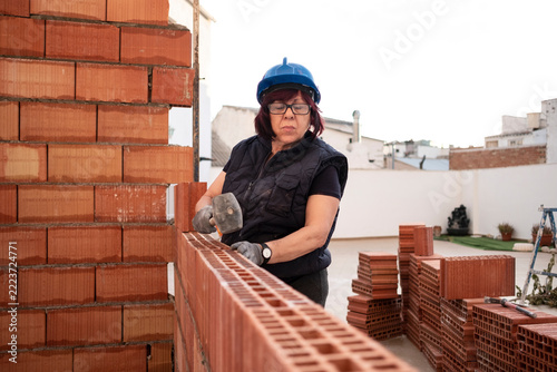 mature woman bricklayer lays bricks in the construction and remodeling of the terrace room of a house