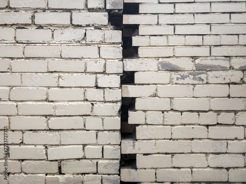 The white old brick wall is divided in half by a crack. Concept of choice.